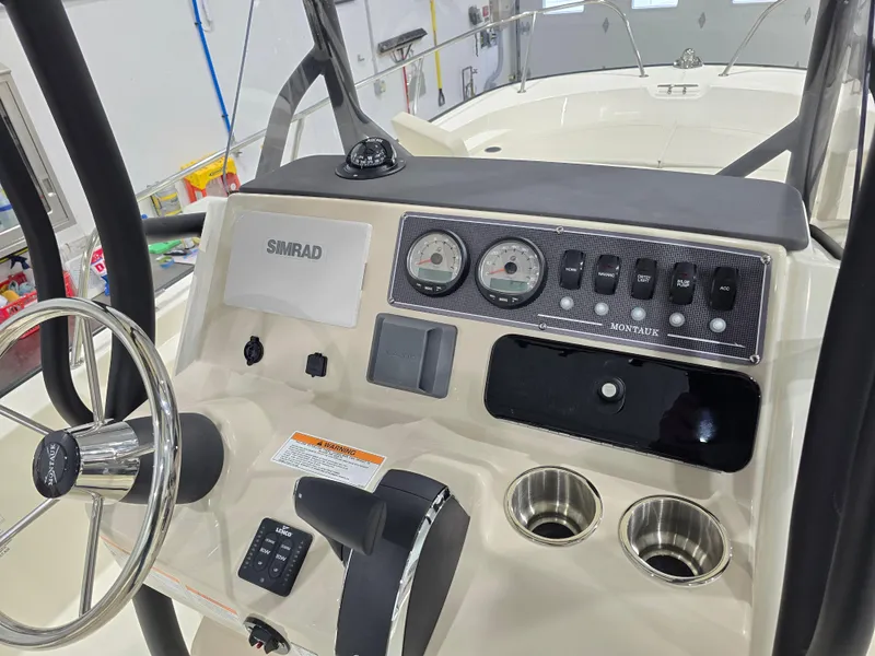 Slide: The Image of 2025 Boston Whaler 210 Montauk boat dashboard with steering wheel and control panel. - 14