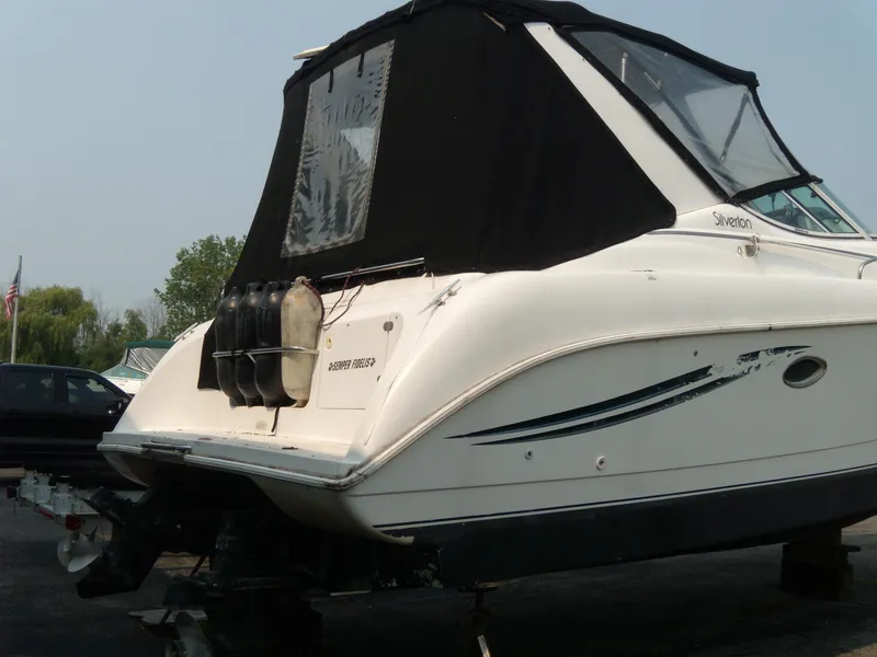 Slide: The Image of 1996 Silverton 310 Express boat with black canopy, docked on land. - 3