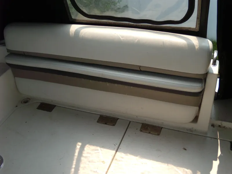Slide: The Image of 1996 Silverton 310 Express boat interior with cushioned seating and window view. - 6