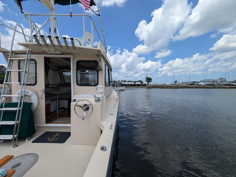 Slide: The Image of Eastern Casco Bay 31 boat docked by calm waters under a partly cloudy sky. - 19