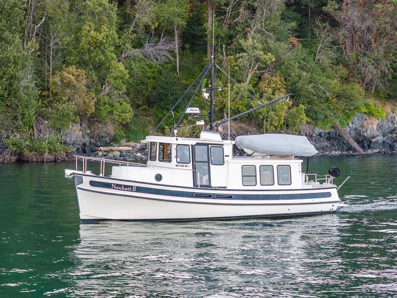 Slide: The Image of 2000 Nordic Tug 32 cruising near a forested shoreline. - 37