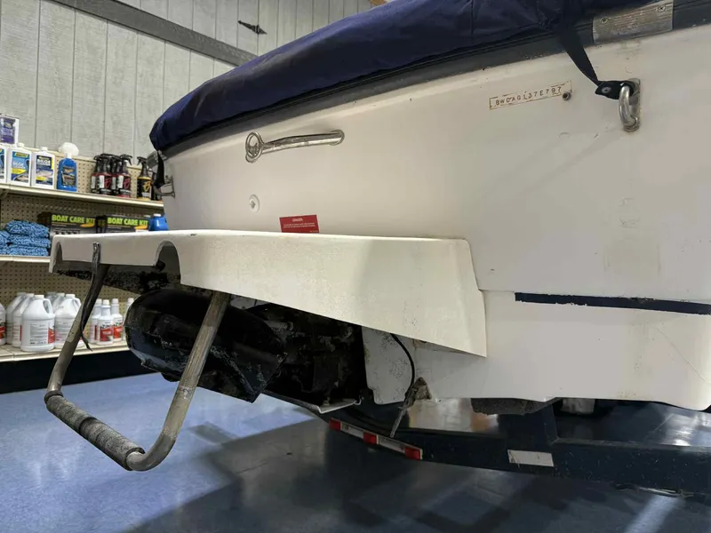 Slide: The Image of 1997 Boston Whaler Rage 15 boat rear view in a store, showcasing ladder and engine. - 13