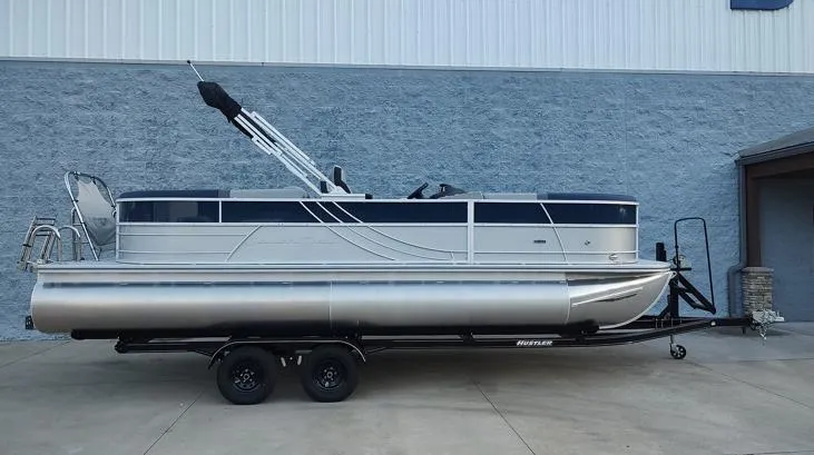 The Image of 2026 South Bay S224RS pontoon boat on trailer, parked outside a building. - 1