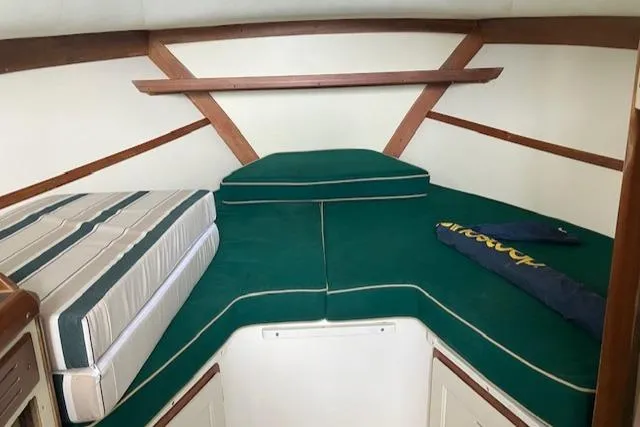 Slide: The Image of 2001 Legacy Boat 28 Express cabin interior with green cushions and wooden accents. - 13