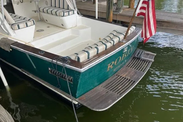Slide: The Image of Legacy Boat 28 Express 2001 docked, featuring striped seating and American flag. - 2