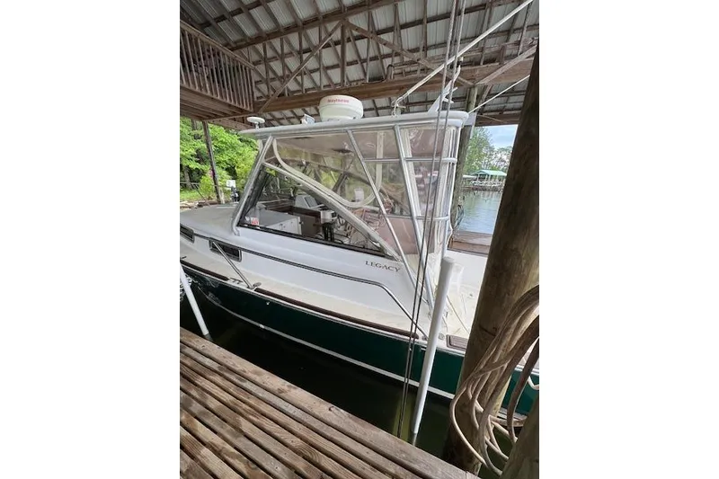 Slide: The Image of 2001 Legacy Boat 28 Express docked under a wooden shelter. - 25