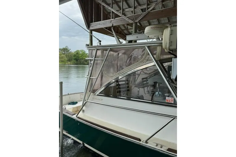 Slide: The Image of 2001 Legacy Boat 28 Express docked under a wooden shelter. - 28