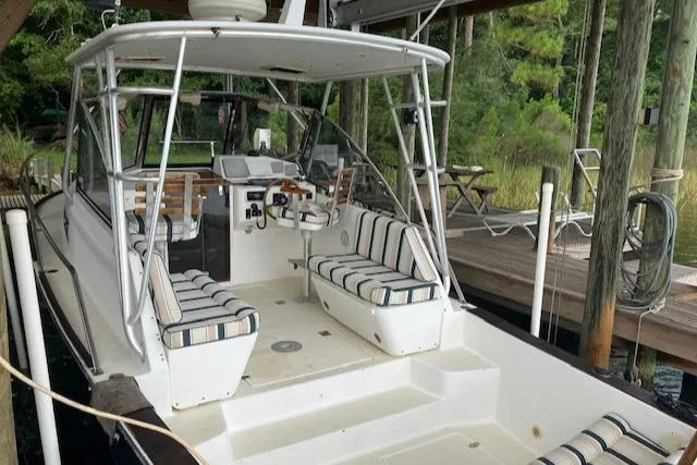 Slide: The Image of 2001 Legacy Boat 28 Express with striped seating, docked in a wooded area. - 3