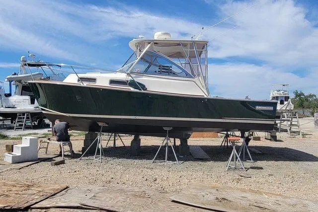 Slide: The Image of 2001 Legacy Boat 28 Express on stands, under clear blue sky. - 31