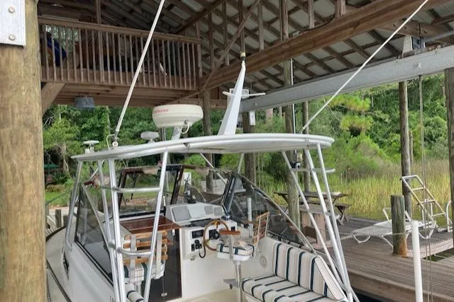 Slide: The Image of 2001 Legacy Boat 28 Express docked under a wooden shelter with lush greenery. - 4