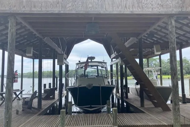 Slide: The Image of 2001 Legacy Boat 28 Express docked under a wooden boathouse. - 9