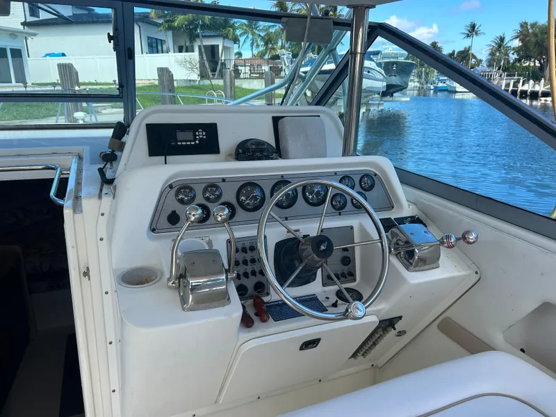 Slide: The Image of 1999 Wellcraft 330 Coastal boat helm with gauges and controls, docked by a waterfront. - 13