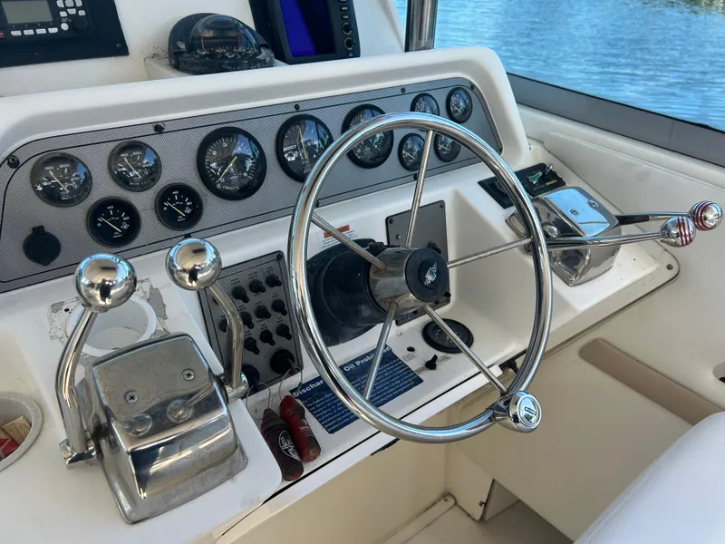 Slide: The Image of 1999 Wellcraft 330 Coastal boat dashboard with steering wheel and control panel. - 17