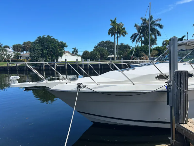 Slide: The Image of 1999 Wellcraft 330 Coastal boat docked by palm trees and waterfront homes. - 2