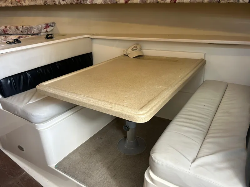 Slide: The Image of 1999 Wellcraft 330 Coastal cabin interior with dining table and cushioned seating. - 25