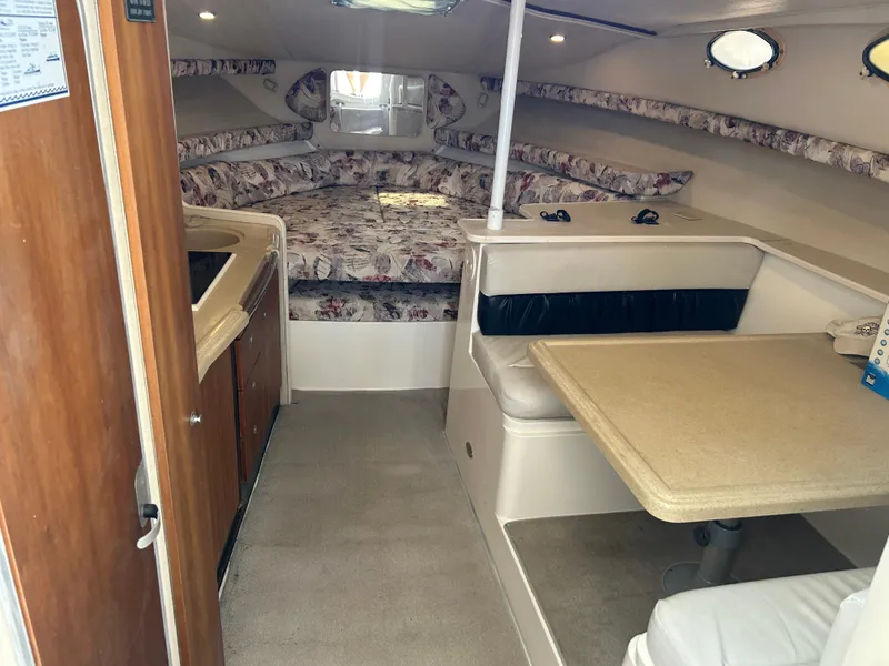 Slide: The Image of 1999 Wellcraft 330 Coastal cabin interior with seating, table, and bed. - 29