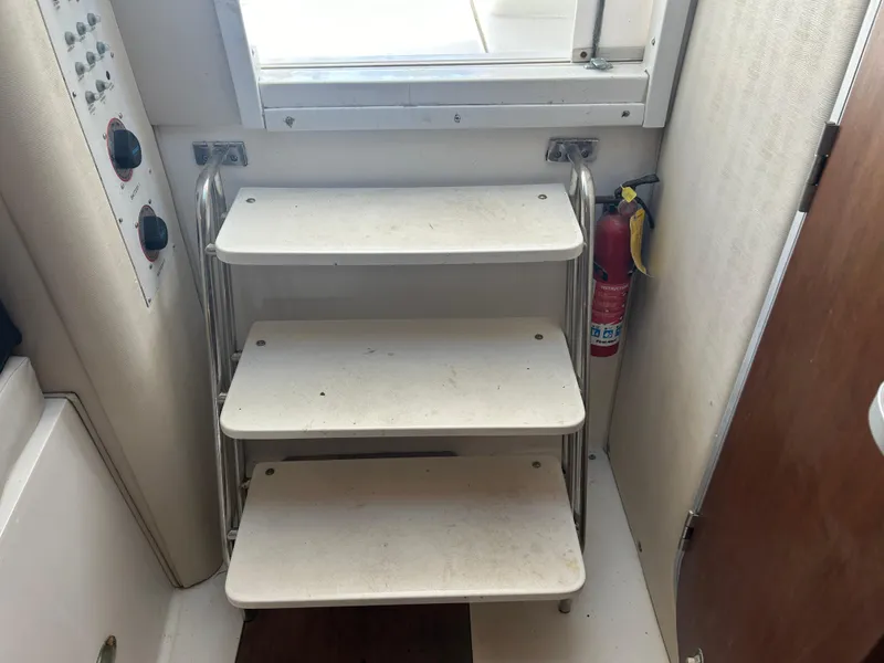 Slide: The Image of 1999 Wellcraft 330 Coastal interior steps with fire extinguisher and control panel. - 49