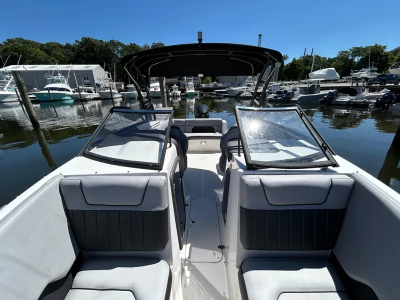 Slide: The Image of 2019 Rinker Q5 OB boat docked in marina, featuring red and white exterior. - 12