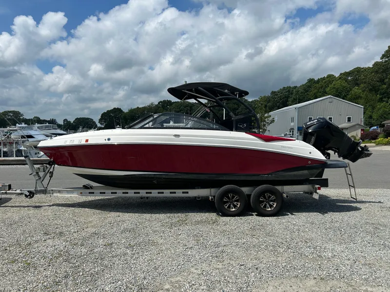 Slide: The Image of 2019 Rinker Q5 OB boat with red and white design on a calm lake. - 2