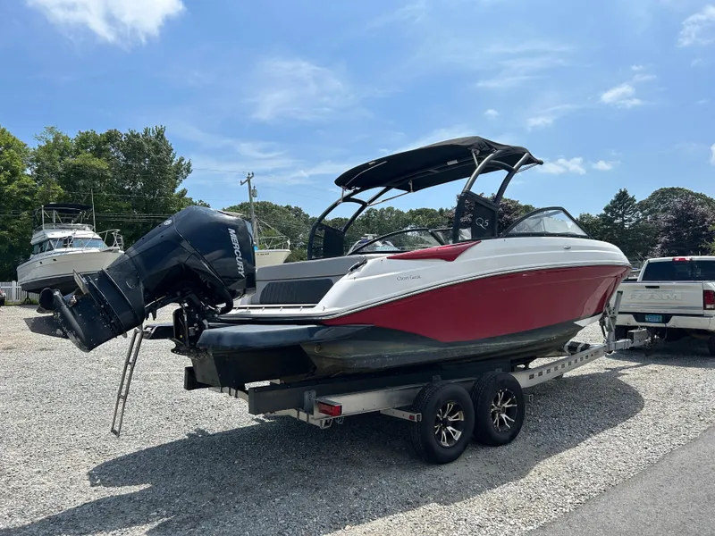 Slide: The Image of 2019 Rinker Q5 OB boat on trailer, red and white design, parked outdoors. - 9