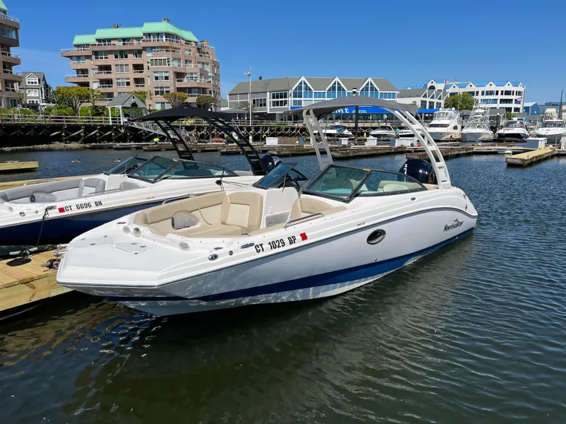 The Image of 2022 NauticStar 243 DC boat docked in a marina with waterfront buildings. - 0