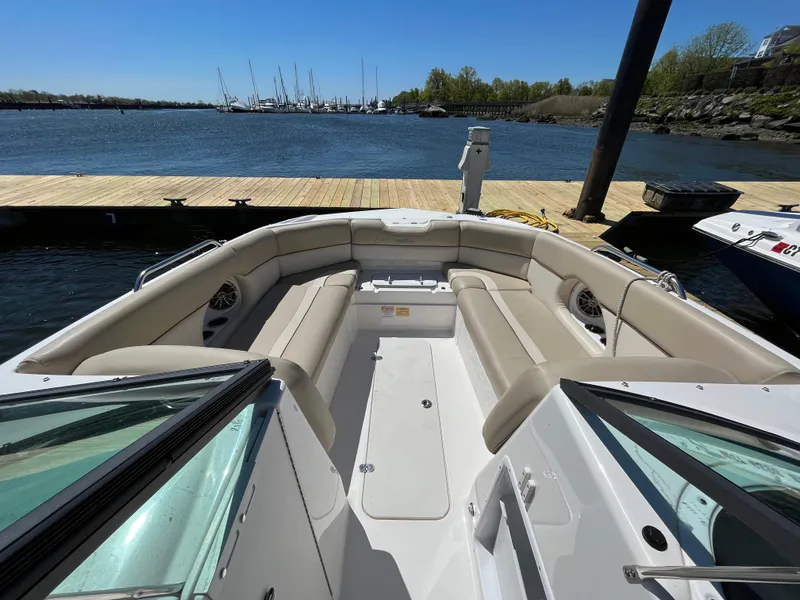 Slide: The Image of 2022 NauticStar 243 DC boat docked, featuring spacious seating and scenic waterfront view. - 23