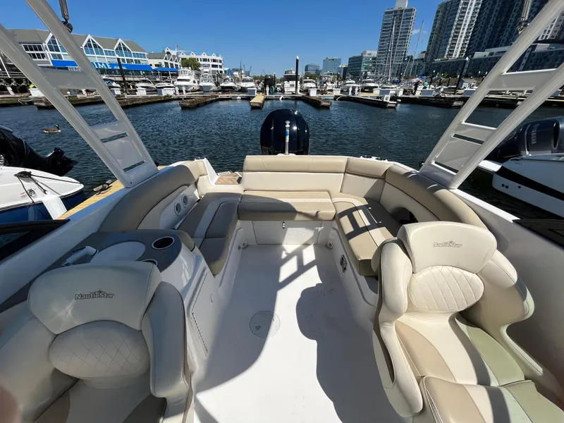 Slide: The Image of 2022 NauticStar 243 DC boat interior with luxurious seating in a marina setting. - 25