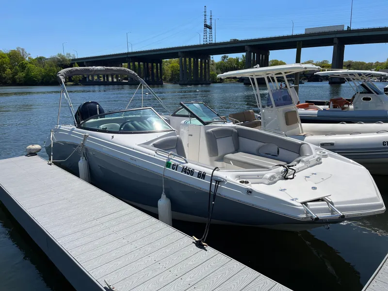 Slide: The Image of 2022 NauticStar 243 DC boat docked by a river under a bridge. - 1