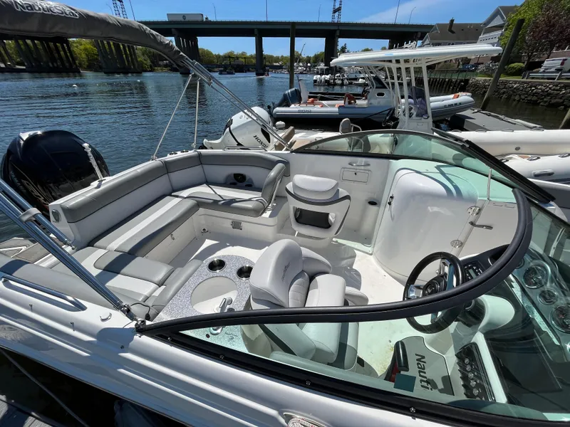 Slide: The Image of 2022 NauticStar 243 DC boat with spacious seating, docked by the water. - 26