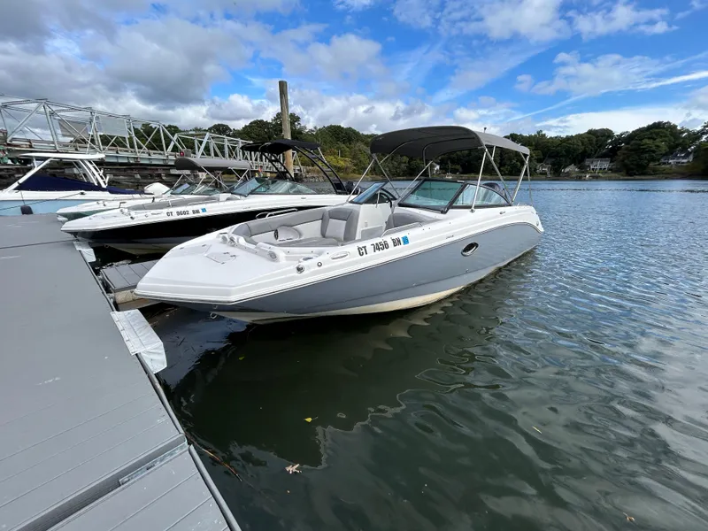 Slide: The Image of 2022 NauticStar 243 DC boat docked on a calm lake under a blue sky. - 4