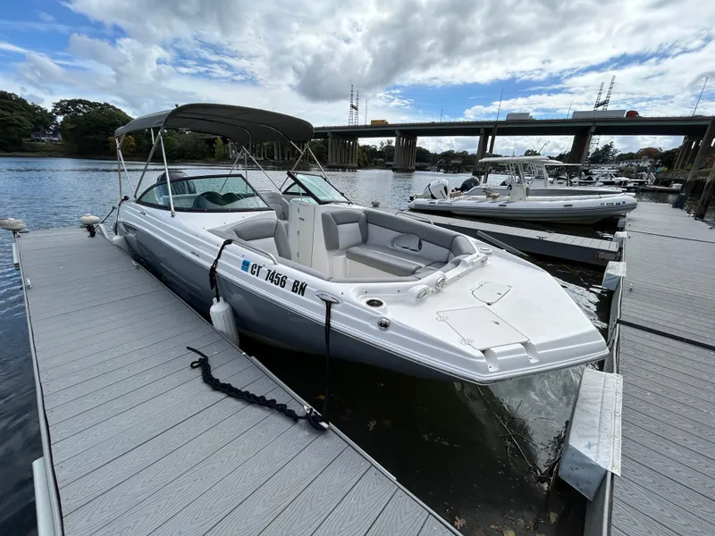 Slide: The Image of 2022 NauticStar 243 DC boat docked on a calm river under cloudy skies. - 5