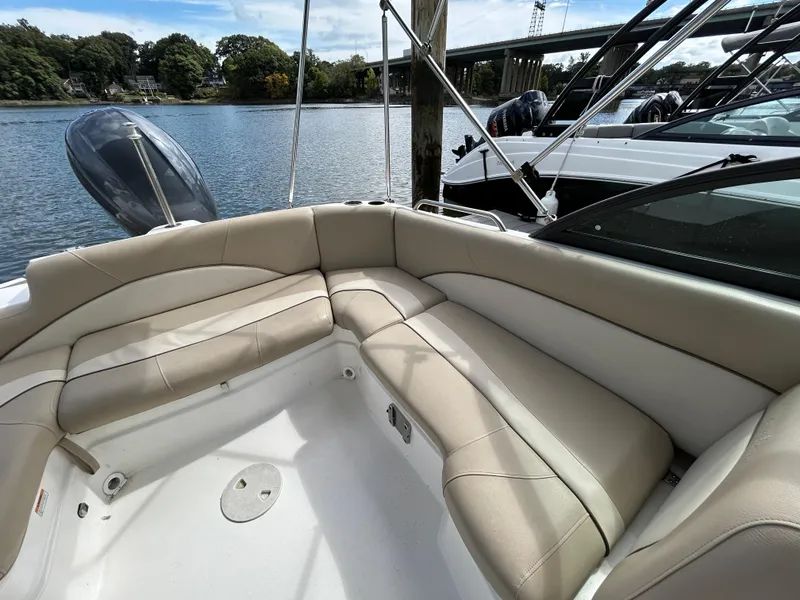 Slide: The Image of 2021 NauticStar 203DC Sport Deck boat with beige seating, docked by a scenic river. - 17