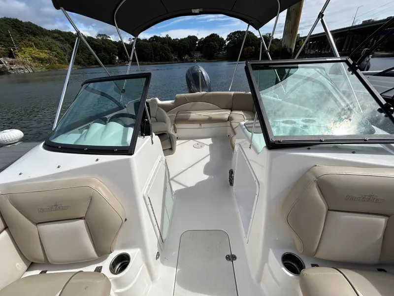 Slide: The Image of 2021 NauticStar 203DC Sport Deck boat interior with beige seating and dual windshields. - 6