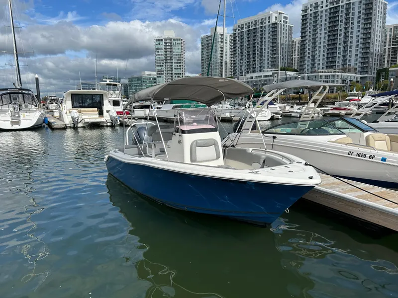 Slide: The Image of 2021 NauticStar 2102 Legacy boat docked in marina, city skyline in background. - 1