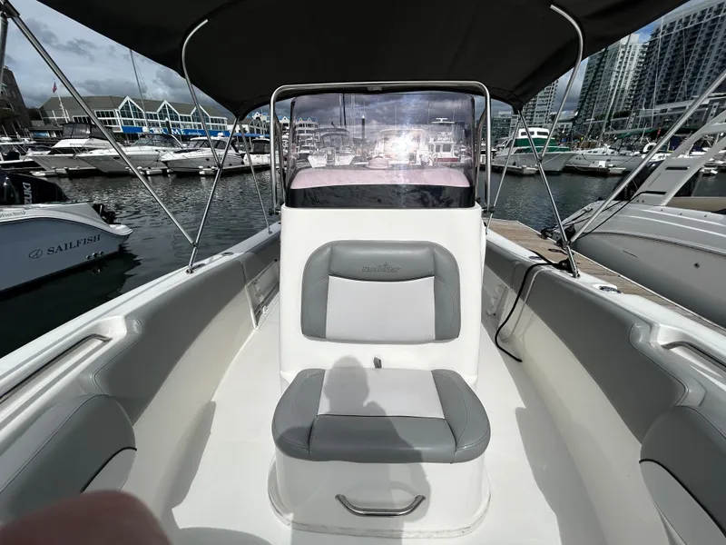 Slide: The Image of 2021 NauticStar 2102 Legacy boat interior at marina, featuring seating and console. - 14