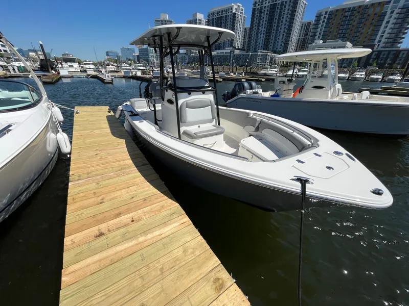Slide: The Image of 2021 NauticStar 2302 Legacy boat on water with Yamaha engine, clear sky background. - 2