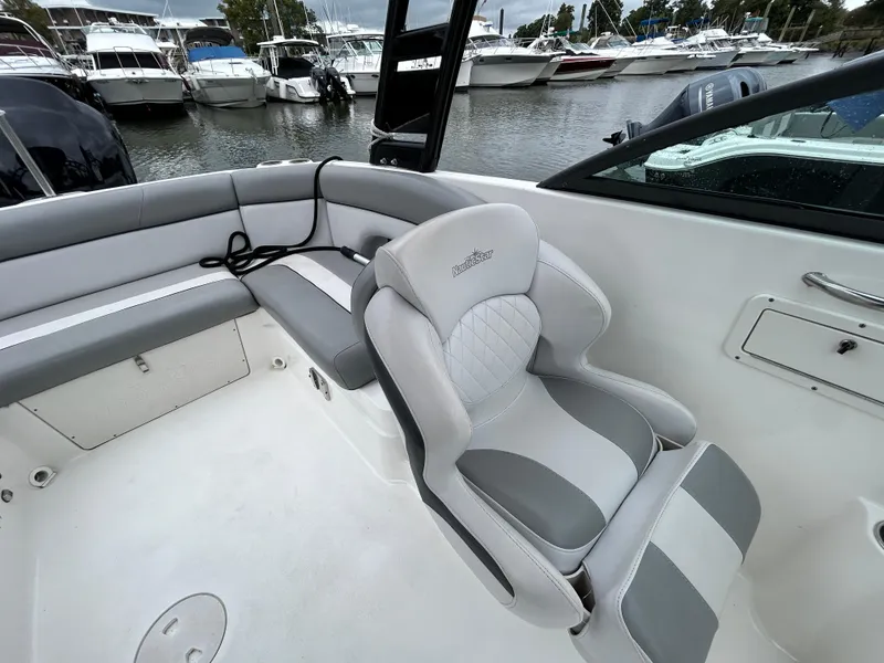 Slide: The Image of 2021 NauticStar 243 DC boat interior with gray seating, docked at marina. - 17