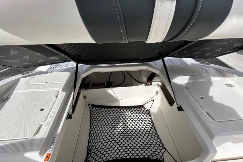 Slide: The Image of 2026 Chaparral 21 SSi OB boat storage compartment with open hatch and netting. - 11