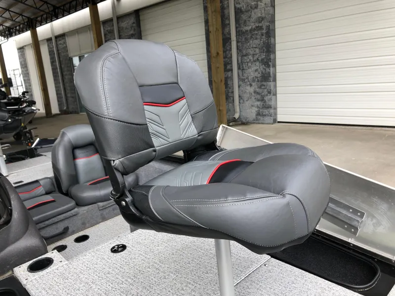Slide: The Image of 2021 Bass Tracker PRO TEAM 175 TXW boat seat, gray with red accents, in a showroom. - 14