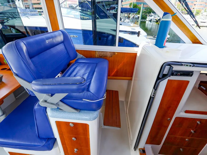 Slide: The Image of Captain's chair on 2004 True North 38 boat, featuring blue upholstery and wooden accents. - 22