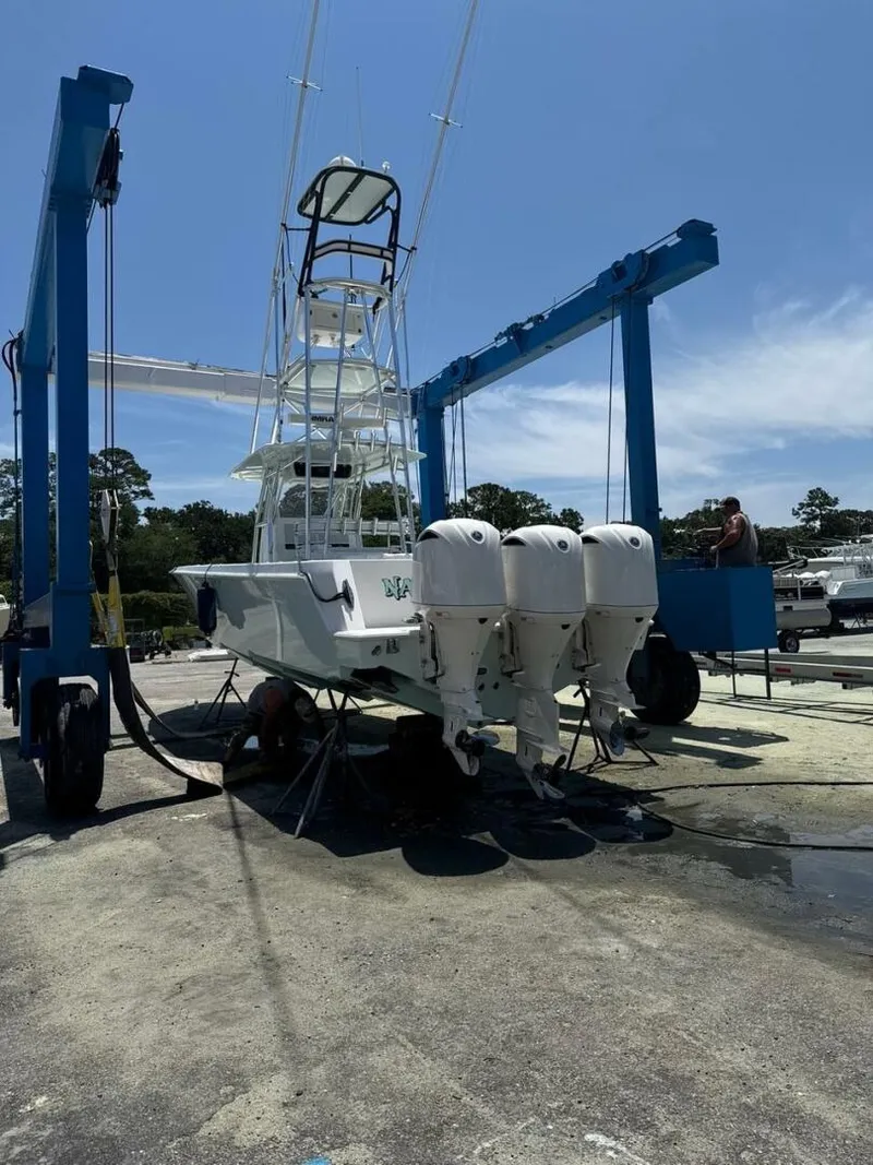 Slide: The Image of 2012 Contender 39ST boat with triple outboard engines on a lift under clear sky. - 11