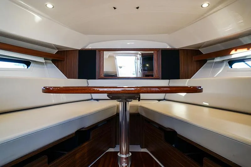 Slide: The Image of 2018 Pursuit OS 355 Offshore cabin interior with seating and wooden table. - 11