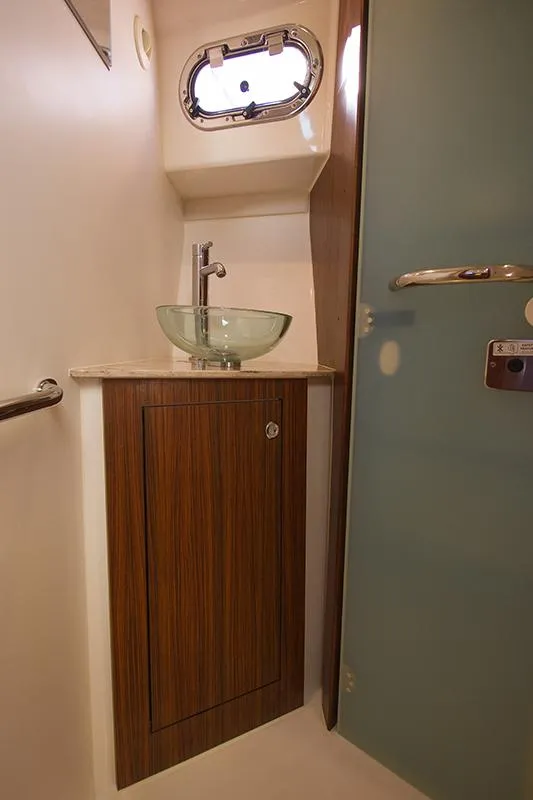 Slide: The Image of 2018 Pursuit OS 355 Offshore bathroom with glass sink and wooden cabinet. - 14