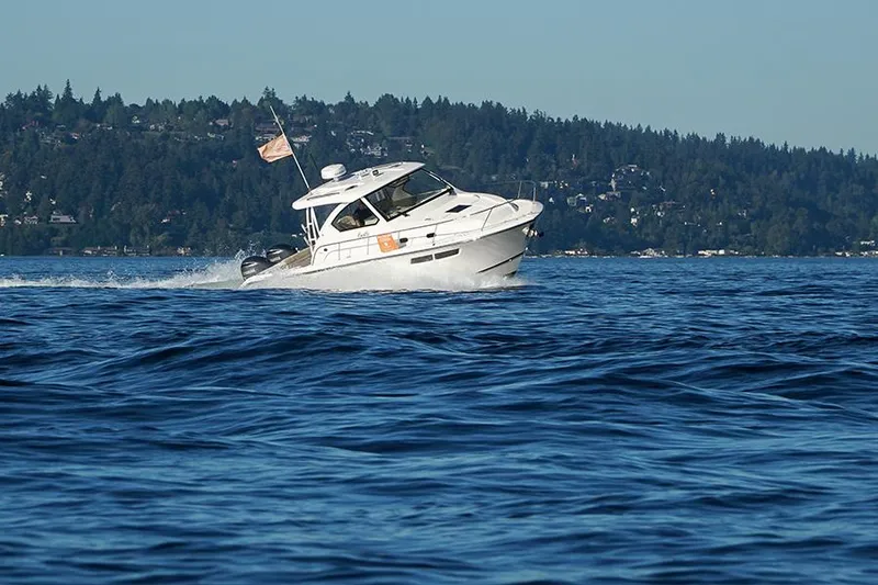 Slide: The Image of 2018 Pursuit OS 355 Offshore boat cruising on a scenic lake with forested hills. - 18