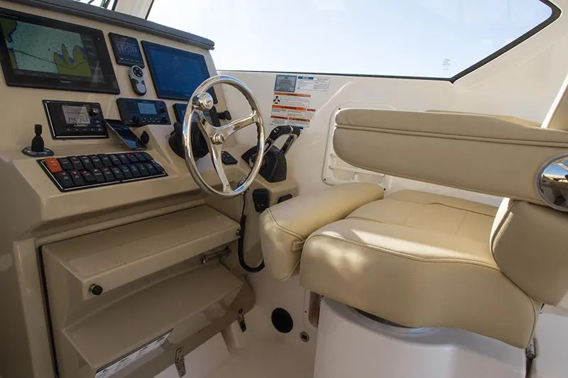 Slide: The Image of 2018 Pursuit OS 355 Offshore helm with navigation screens and beige seating. - 5