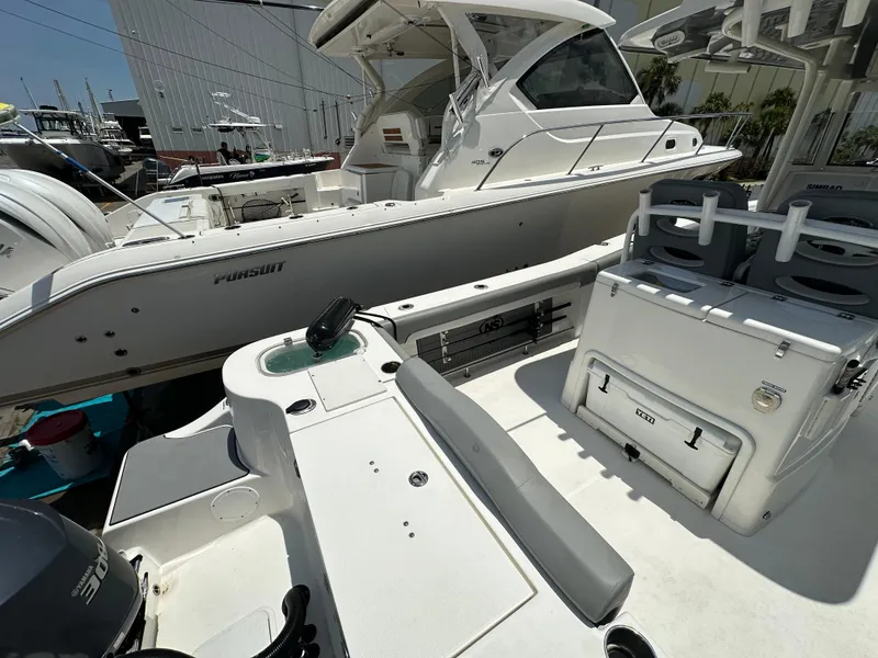 Slide: The Image of 2021 NauticStar 28XS boat interior with seating and storage, docked beside another vessel. - 12