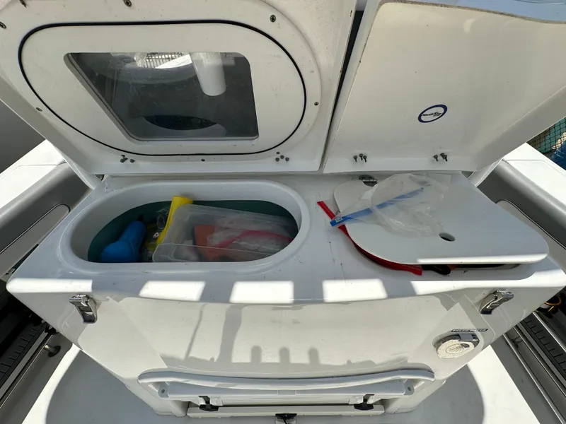Slide: The Image of Open storage compartment on a 2021 NauticStar 28XS boat, containing various items. - 17