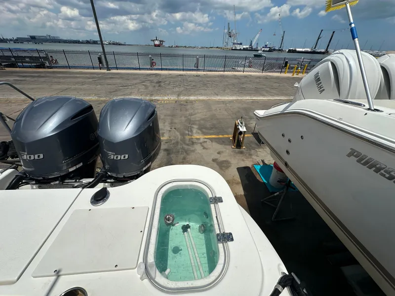 Slide: The Image of 2021 NauticStar 28XS boat with twin Yamaha 300 engines at a dockside marina. - 19