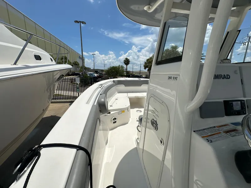Slide: The Image of 2021 NauticStar 28XS boat interior with console and seating, docked under a sunny sky. - 22