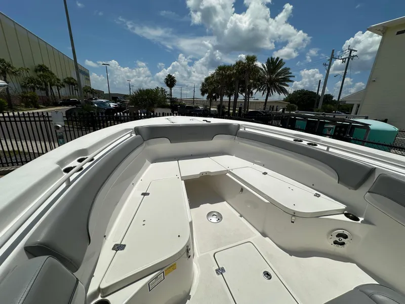Slide: The Image of 2021 NauticStar 28XS boat interior with seating and storage, under a partly cloudy sky. - 24